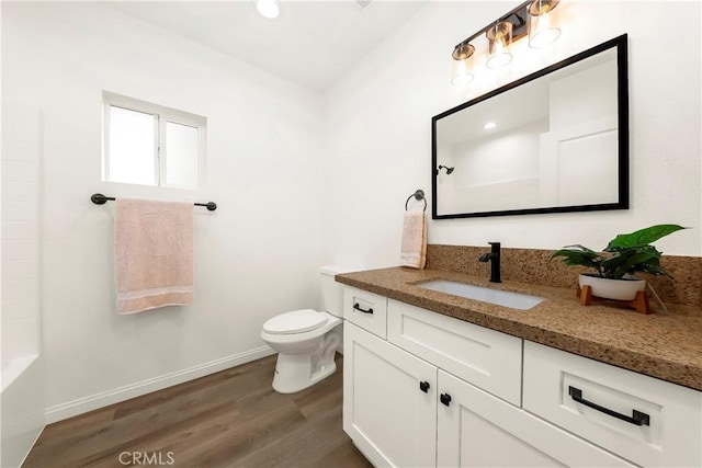 bathroom with toilet, baseboards, wood finished floors, and vanity