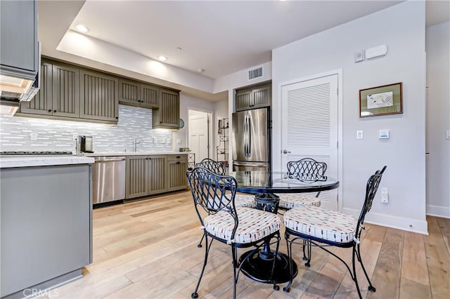 kitchen with sink, light wood-type flooring, stainless steel appliances, and tasteful backsplash