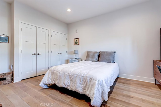 bedroom with multiple closets and light hardwood / wood-style flooring