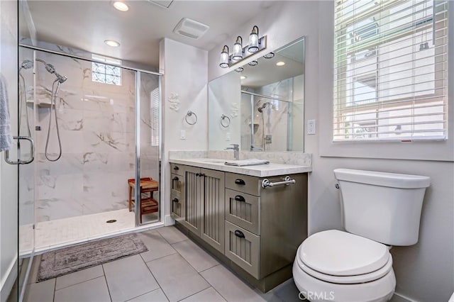 bathroom with tile patterned floors, a shower with door, vanity, and toilet