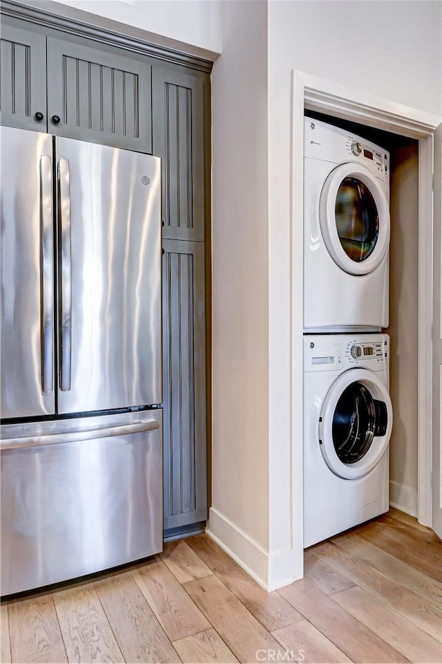 clothes washing area with light wood-type flooring and stacked washer / dryer