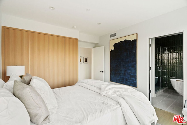 bedroom with light tile patterned floors, connected bathroom, and a closet