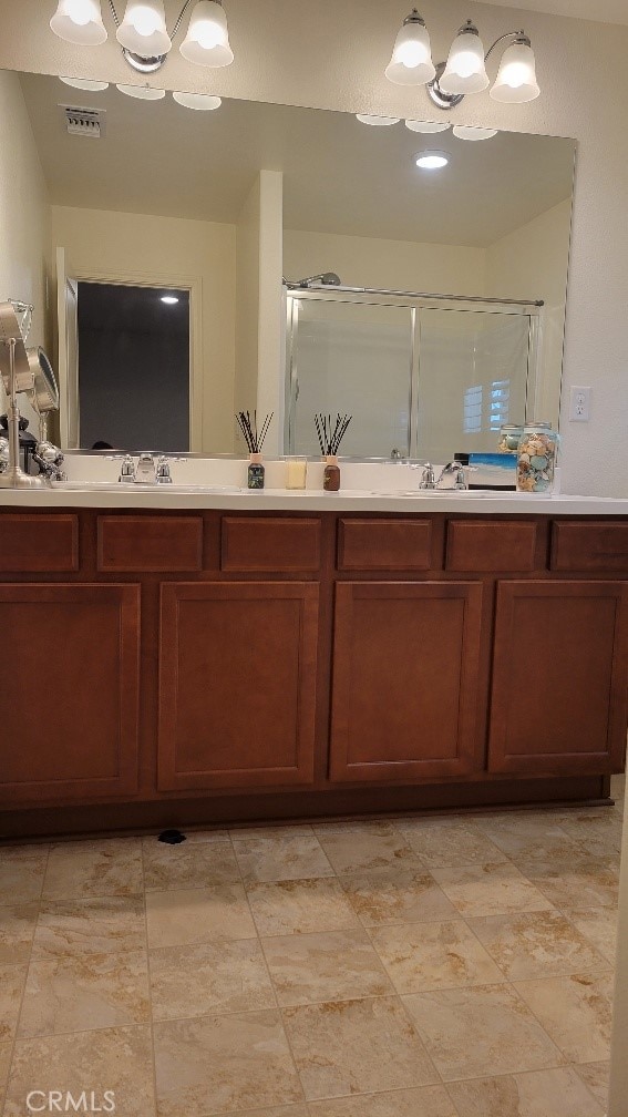 bathroom with a chandelier, vanity, and walk in shower