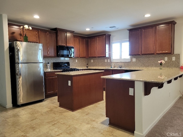 kitchen with black appliances, kitchen peninsula, a breakfast bar area, and tasteful backsplash