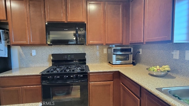 kitchen featuring tasteful backsplash, light stone counters, and black appliances