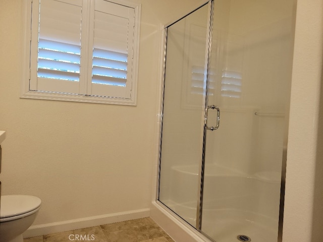 bathroom featuring tile patterned flooring, a shower with shower door, and toilet