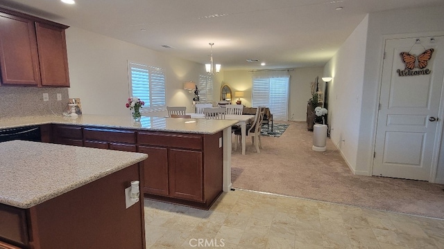 kitchen featuring decorative backsplash, kitchen peninsula, light colored carpet, a kitchen island, and hanging light fixtures