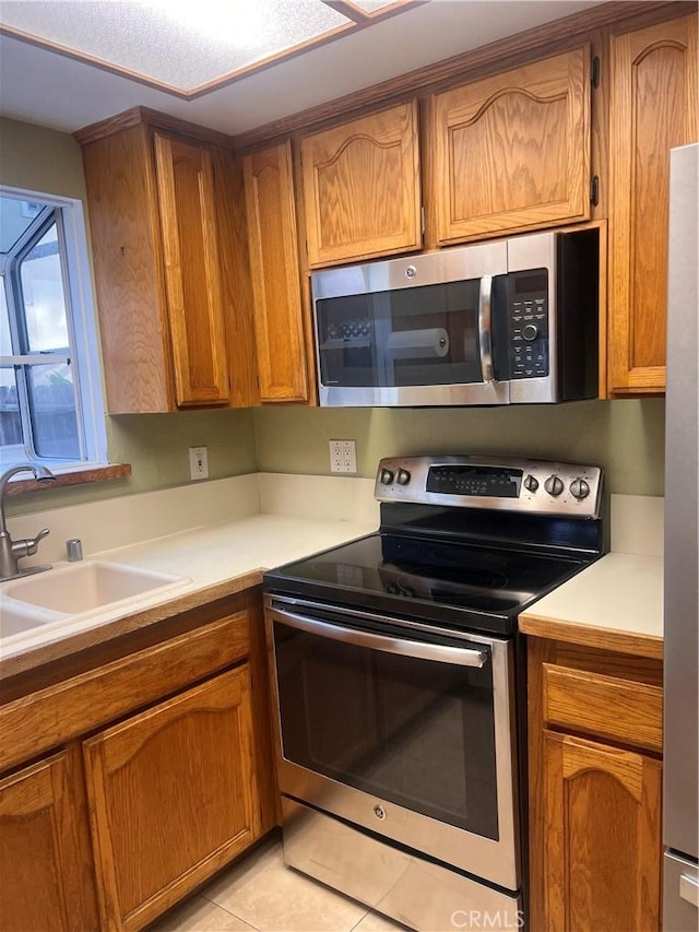 kitchen with appliances with stainless steel finishes, sink, and light tile patterned floors