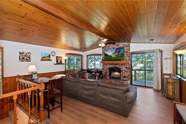 living room with lofted ceiling, wood ceiling, ceiling fan, hardwood / wood-style flooring, and a brick fireplace