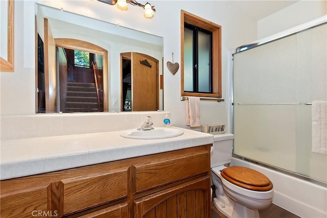 full bathroom featuring enclosed tub / shower combo, vanity, and toilet