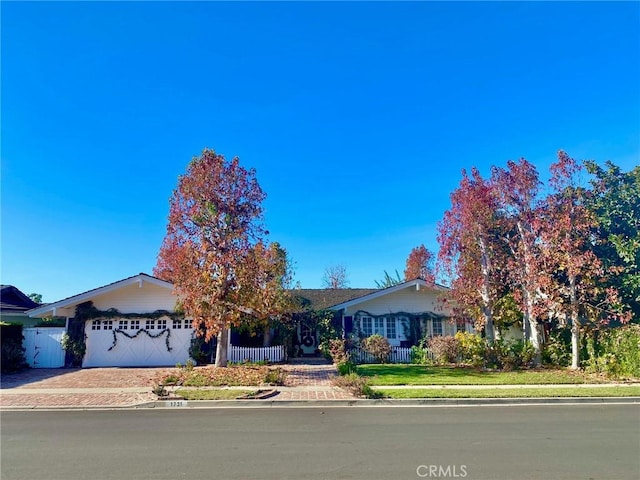 view of front of house featuring a garage, fence, and decorative driveway