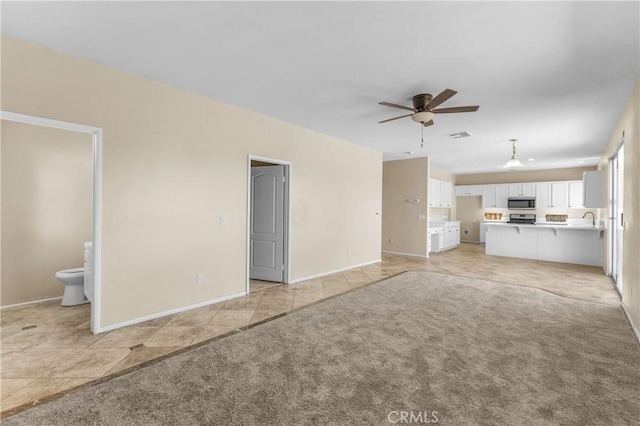 unfurnished living room featuring ceiling fan, sink, and light tile patterned flooring