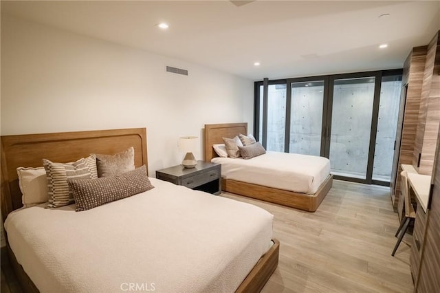 bedroom featuring floor to ceiling windows, light hardwood / wood-style floors, and access to outside