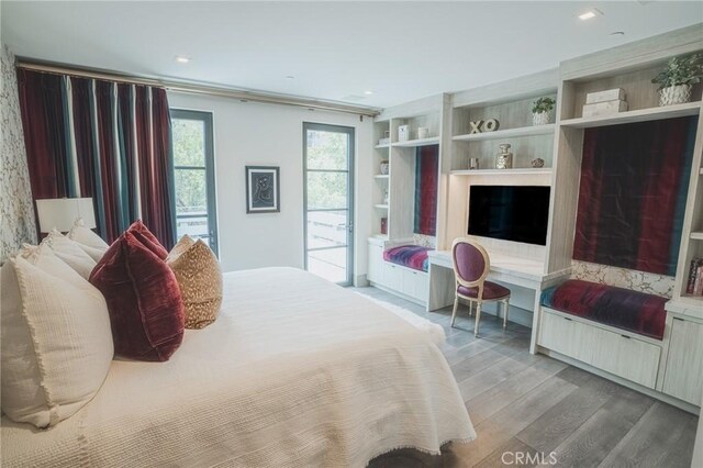 bedroom featuring access to exterior, built in desk, and wood finished floors