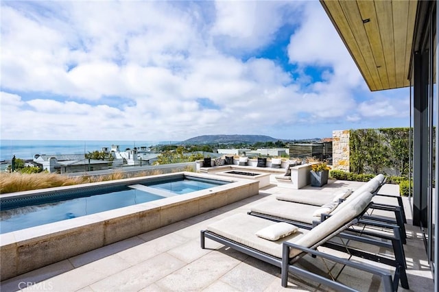 view of pool featuring a water view and an in ground hot tub