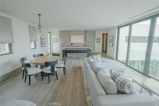 dining space with a wall of windows, baseboards, and light wood-style flooring