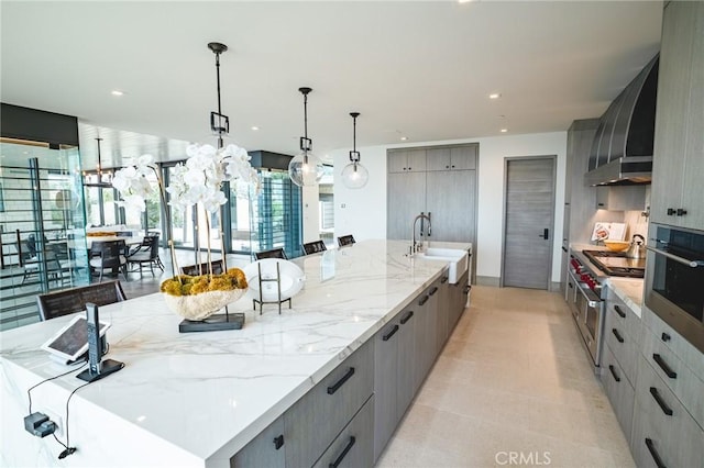 kitchen featuring gray cabinetry, stainless steel appliances, pendant lighting, wall chimney exhaust hood, and a spacious island