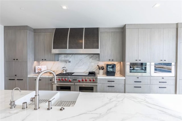 kitchen featuring stainless steel appliances, wall chimney exhaust hood, and gray cabinets