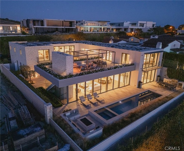 rear view of house featuring a patio area, a balcony, fence, and a pool with connected hot tub