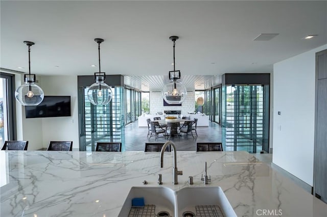 kitchen with decorative light fixtures, plenty of natural light, marble finish floor, and light stone countertops