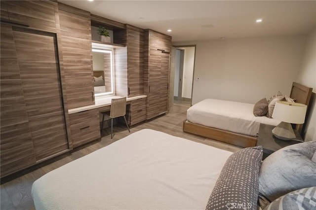 bedroom with built in desk, recessed lighting, and wood finished floors