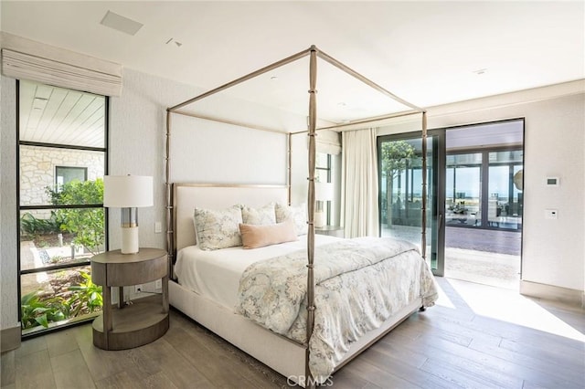 bedroom with multiple windows, wood finished floors, and access to outside