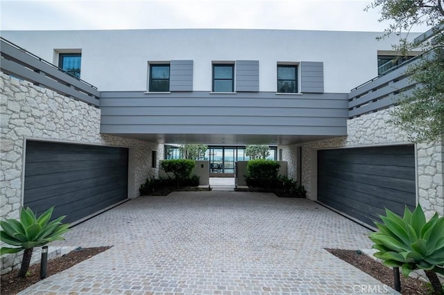 modern home with a carport, stucco siding, and decorative driveway