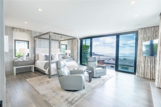 bedroom featuring wood finished floors, access to exterior, and floor to ceiling windows