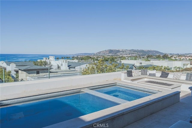 view of swimming pool with an in ground hot tub, an outdoor fire pit, and a water view