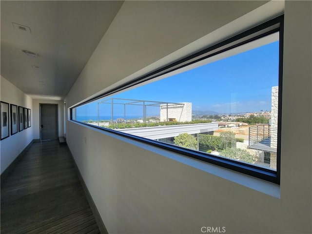 corridor featuring a city view, baseboards, and wood finished floors