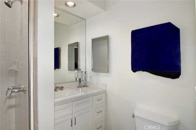 bathroom with tiled shower, vanity, and toilet