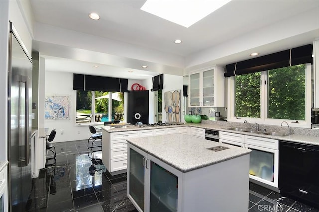 kitchen featuring appliances with stainless steel finishes, a center island, white cabinetry, and sink