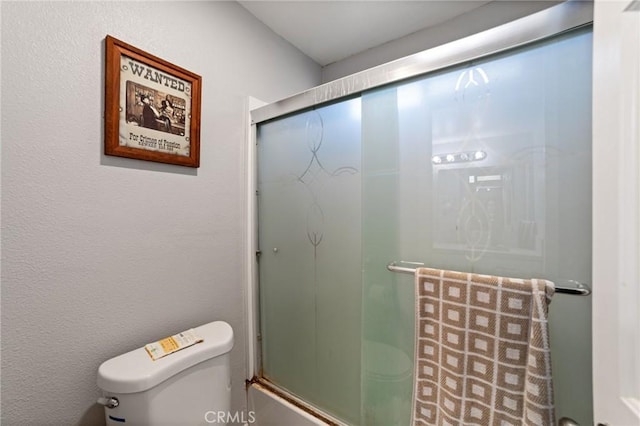 bathroom featuring toilet and combined bath / shower with glass door