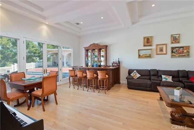 interior space with bar area, french doors, light wood-type flooring, and a high ceiling