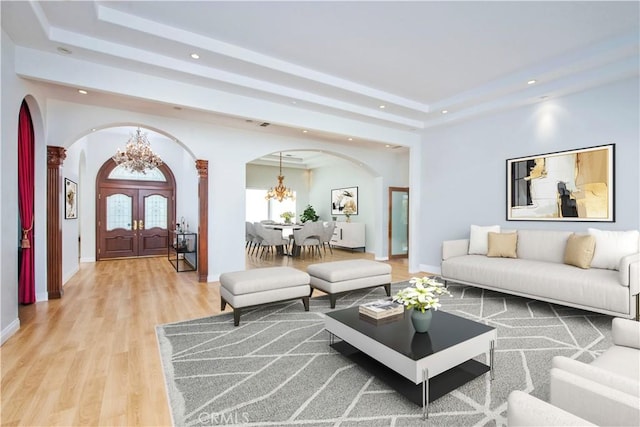 living room featuring a chandelier, wood-type flooring, and decorative columns