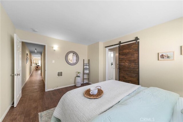 bedroom with dark wood-type flooring and a barn door