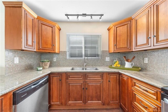 kitchen featuring tasteful backsplash, stainless steel dishwasher, sink, and light stone counters