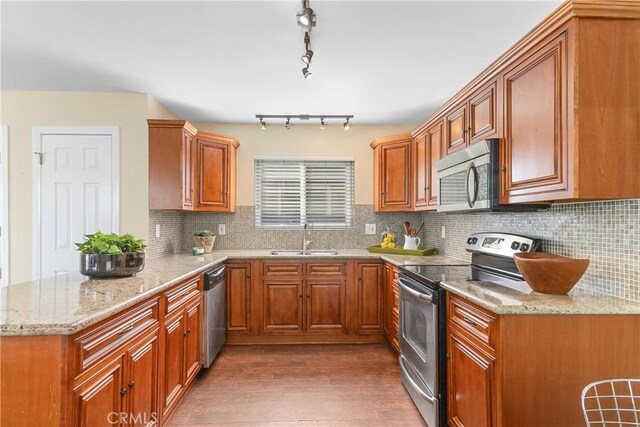 kitchen featuring dark wood-type flooring, appliances with stainless steel finishes, light stone countertops, and sink