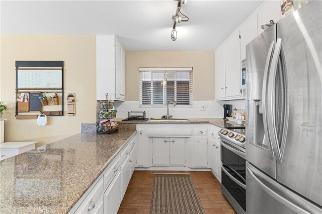 kitchen with white cabinetry, stainless steel appliances, light stone countertops, and sink