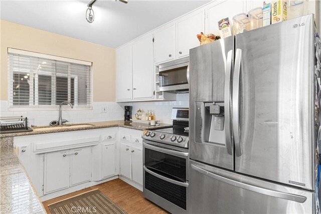 kitchen with appliances with stainless steel finishes, sink, white cabinets, and decorative backsplash