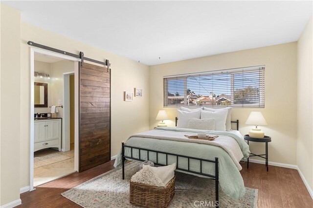 bedroom featuring dark wood-type flooring, ensuite bathroom, and a barn door