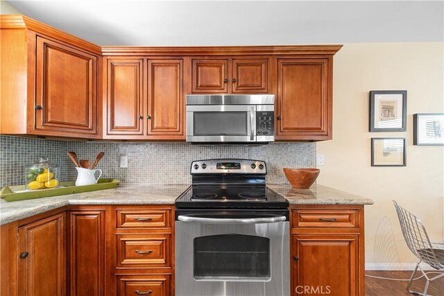 kitchen featuring light stone countertops, appliances with stainless steel finishes, and backsplash