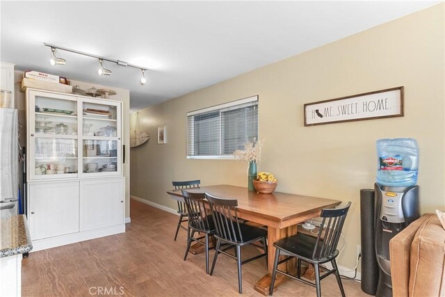 dining room with wood-type flooring and rail lighting