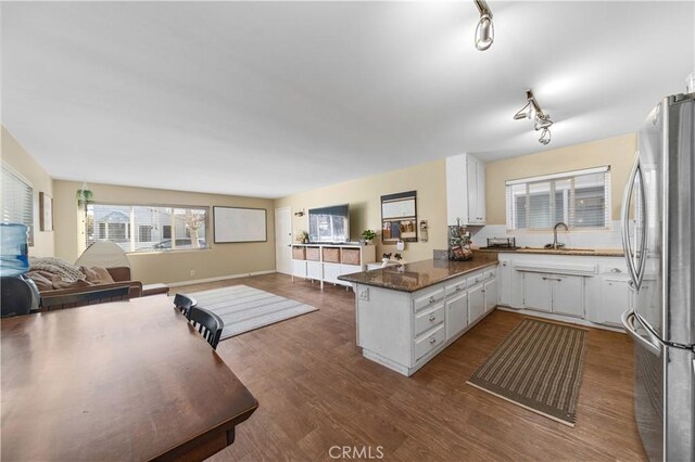 kitchen with sink, dark wood-type flooring, stainless steel refrigerator, white cabinets, and kitchen peninsula