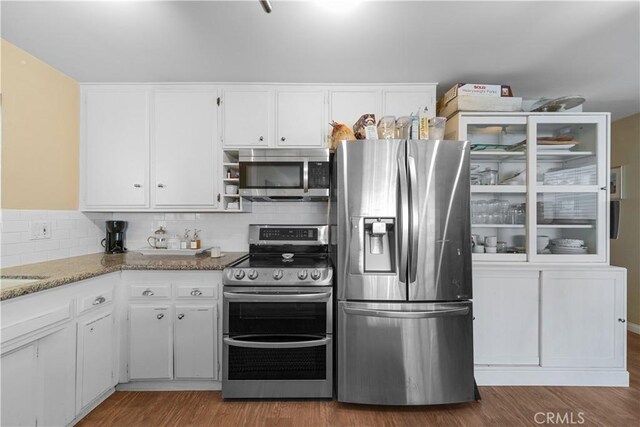 kitchen with white cabinetry, appliances with stainless steel finishes, stone countertops, and hardwood / wood-style floors