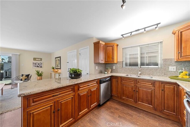 kitchen featuring stainless steel dishwasher, plenty of natural light, kitchen peninsula, and sink