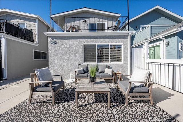 back of property featuring a balcony, an outdoor living space, and a patio