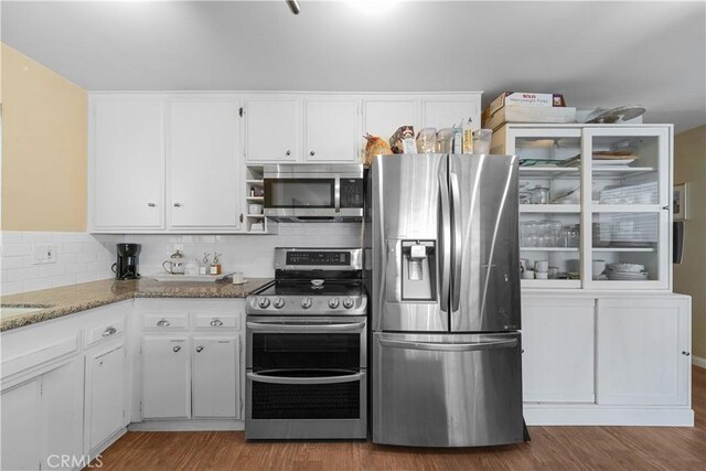 kitchen featuring stone counters, hardwood / wood-style flooring, white cabinets, and appliances with stainless steel finishes