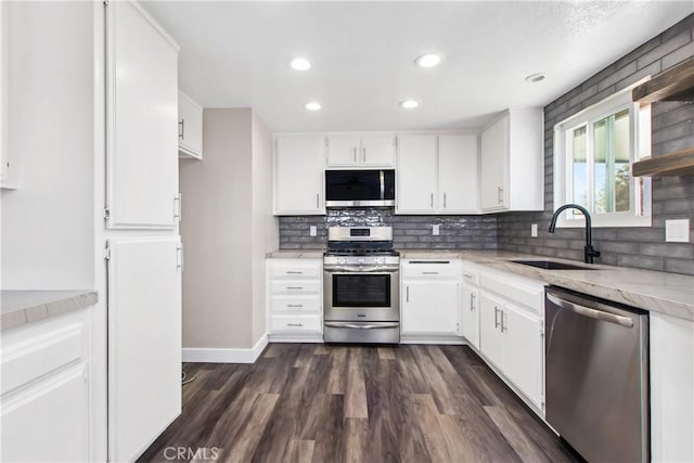 kitchen with dark hardwood / wood-style floors, stainless steel appliances, backsplash, white cabinets, and sink