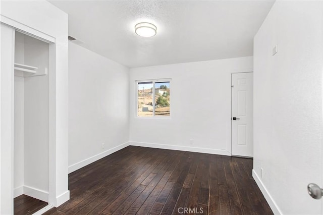 unfurnished bedroom with dark hardwood / wood-style flooring, a closet, and a textured ceiling